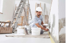A painter in a customer's home painting a wall.
