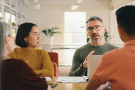A freelancer sat around a table with his client addressing an unpaid invoice.